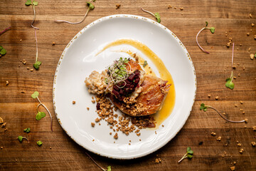 Top View of Duck Confit on Plate against Butcher Block Cutting Board