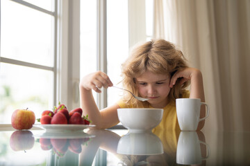 Unhappy little boy child sit at table at home kitchen have no appetite for healthy breakfast. Upset...