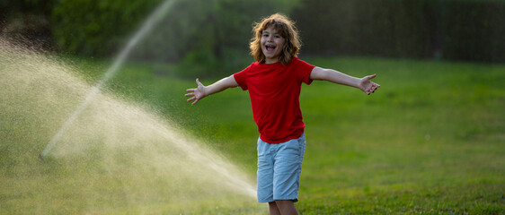 Child playing at summer backyard. Water fun in garden. Kid play with water sprinkler in garden. Funny little boy playing with garden watering hose in yard. Child having fun with spray of water.