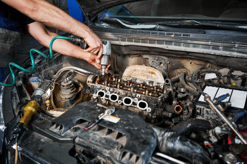 Close up of repairman, mechanic repairing, fixing car engine. Man worker working in garage,...