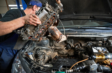 Repairman, mechanic worker making diagnostics of car, examining engine. Man wearing cap and uniform...