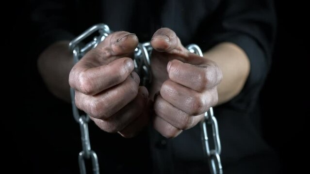 Fight with chain in hands indoor. A view of fighting dirty female hands in chain against black background.