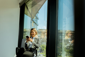 Businesswoman talking on phone in bright modern office on a sunny day