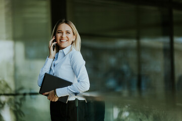 Businesswoman engaged in a phone call outside office building on sunny afternoon