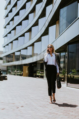 Business professional walking outside modern office building on a sunny day
