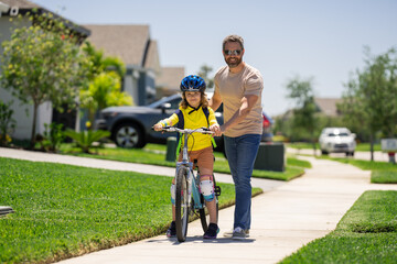 Father and son in a helmet riding bike. Little cute adorable caucasian boy in safety helmet riding bike with father. Family outdoors summer activities. Fathers day. Childhood and fatherhood.