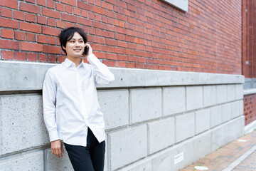 壁にもたれて電話をしている男性