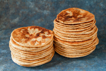 Flatbread lavash, chapati, naan, heap of tortilla on a blue background Homemade flatbread stacked.