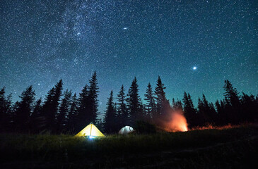 Night camping under sky full of stars and Milky way in the mountains. Starry sky over illuminated...