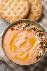 Htipiti or Tirokafteri a delicious Greek feta and roasted red pepper dip closeup on the bowl on the table. Vertical top view from above