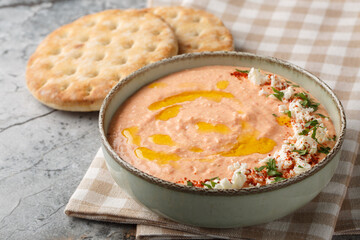 Greek Tirokafteri spread is a  spicy feta dip with feta cheese, roasted red peppers, garlic and chilli closeup on the bowl on the table. Horizontal