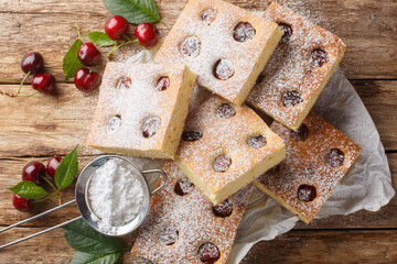 Fruity cherry cake known as Bublanina sprinkled with powdered sugar closeup on the parchment on the...