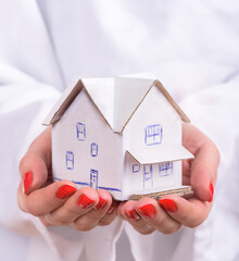 Concept of sweet home of dream. Woman hold house from paper in hands. Your property.