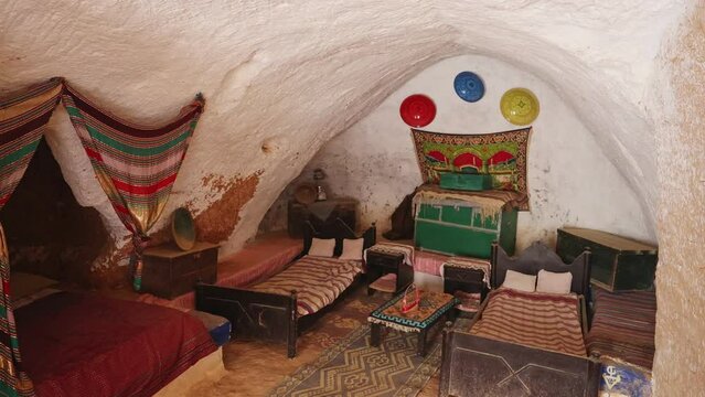  Modestly furnished cozy sleeping area in ancient Berber cave dwelling in Matmata, with double bed for home owners, decorated with traditional textiles. History of indigenous peoples of Tunisia