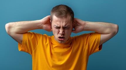 Naklejka premium A man in a yellow shirt places his hands over his ears