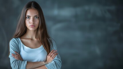 Fototapeta premium A beautiful young woman poses with crossed arms in front of a chalkboard backdrop