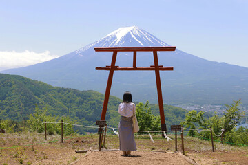 girl praying under a red Torii with the background of Mt. fuji 