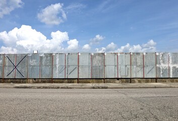 Long row of empty metal boards for street billboards at the roadside . Blue sky with clouds above,...
