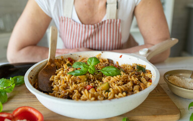 Woman in the kitchen with a healthy cooked gluten free meal with chickpea pasta, vegetables and meat