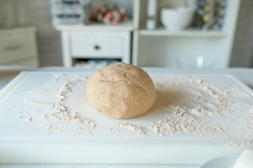 Ball of fresh whole wheat pizza dough on floured surface in the kitchen
