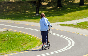 Girl rides an electric scooter in the summer Park
