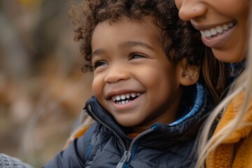 An adorable multiracial preschool age boy laughs while spending time with his moms outside at the park