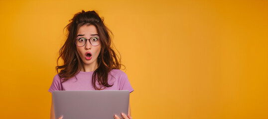 A woman with glasses is holding a laptop and looking surprised. portrait of pretty young girl hold laptop point look scared empty space wear trendy violet outfit isolated on yellow color background
