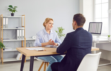 Two business people man and woman sitting at the desk on a meeting. Friendly cheerful woman interviewing new candidate for vacancy company sitting in office. Job seekers and employee recruit concept.
