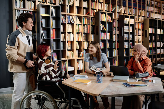 Group of diverse gen Z male and female students gathering in modern university library, copy space