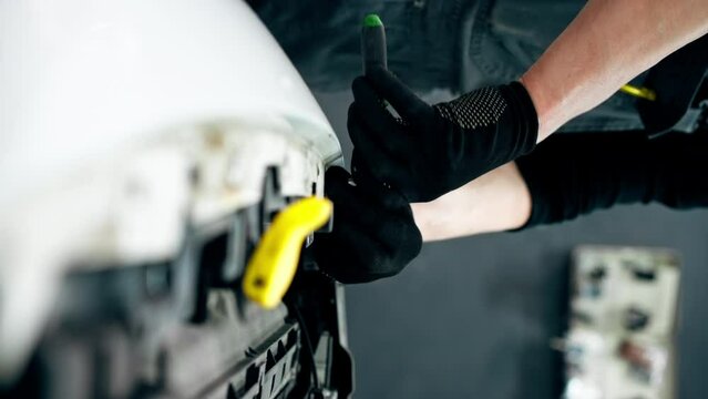 vertical video close up At a service station master auto mechanic unscrews bolts on the interior panel of a white car