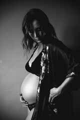 A pregnant woman touches her belly. she is in her underwear and silk gown.