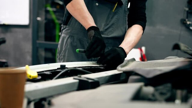 close up At a service station master auto mechanic unscrews bolts on the interior panel of a white car