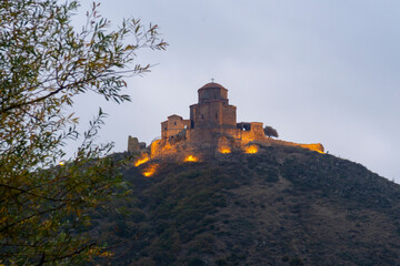 Fototapeta premium Jvari Monastery on the hill illuminated with warm lighting in the early morning