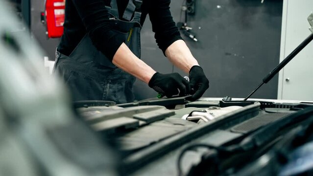 close up At a service station master auto mechanic unscrews bolts on the interior panel of a white car