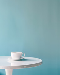Minimalistic white cup on a table against a blue background.