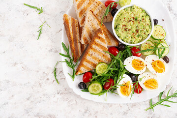 Healthy breakfast. Boiled egg, guacamole, toast and fresh salad. Top view, above