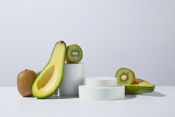 Haircare natural ingredient including kiwi and avocado displayed on white table over the same color background, two blank circular platforms are stacked on top of each other. Displaying space