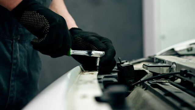 close up At a service station master auto mechanic unscrews bolts on the interior panel of a white car