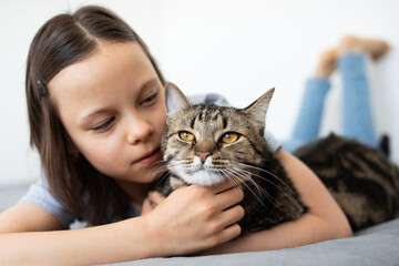 Portrait of little adorable gray cat and little girl indoors