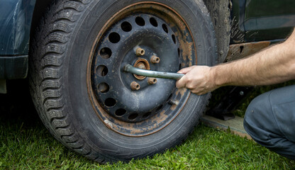 A man meticulously works on the tire of a car, focused on fixing any issues and ensuring it is in...