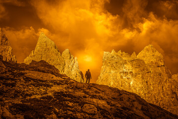 Fantasy orange color effect of panorama with lonely mountaineer in silhouette and magnificent...