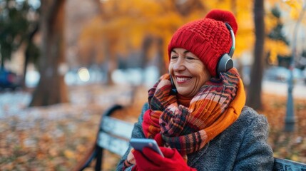 happy stylish middle aged woman in red hat with scarf, smartphone and gloves listening to the music