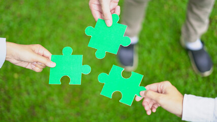 Business leaders collaborate on green partnership, fitting together the pieces of environmental, social, and governance (ESG) strategies for sustainable success, symbolized by a jigsaw puzzle in hand.