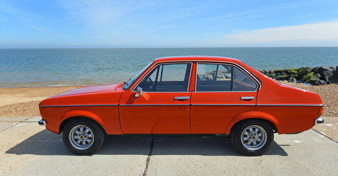 Classic  Ford Escort Mk.II parked on seafront promenade beah and sea in background.