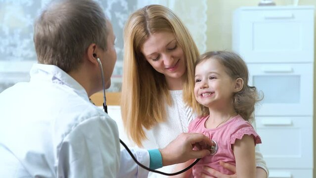 Male pediatrician examines baby with a stethoscope.