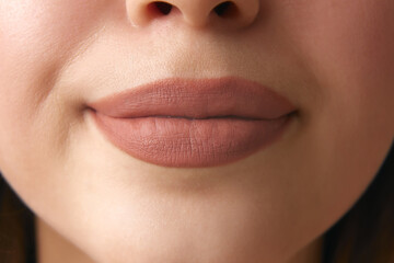 Close up of full, plump female lips with neutral beige lipstick. Facial care procedures. Beautiful...