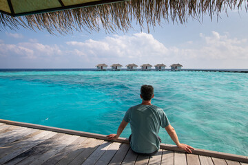 man tourist enjoying sea view in luxury hotel in Maldives, vacation travel, relaxation