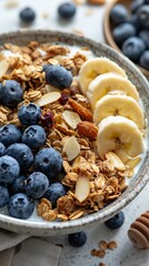 Fototapeta premium A bowl filled with crunchy granola topped with fresh blueberries and slices of ripe banana. The concept of a healthy breakfast.
