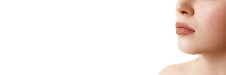 Obraz premium Banner. Cropped photo of female lips with neutral beige make-up, full lips with lipstick against white background with copy space. Concept of female beauty, skin care, cosmetology and cosmetics.