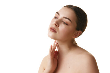 Portrait of young brunette woman with bare shoulders gently touching her neck against white studio background. Concept of natural beauty, antiaging treatment, wellness, youth. Ad